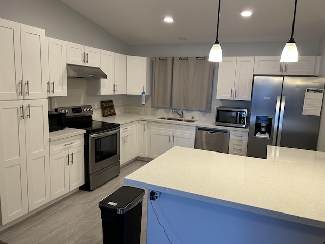 kitchen featuring pendant lighting, white cabinets, stainless steel appliances, and vaulted ceiling