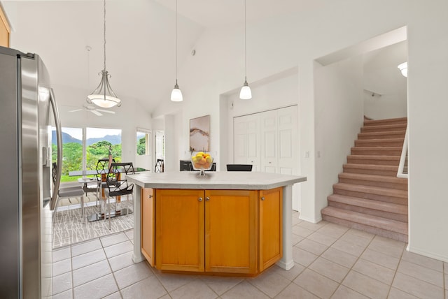 kitchen featuring a center island, stainless steel fridge, light tile patterned floors, and high vaulted ceiling