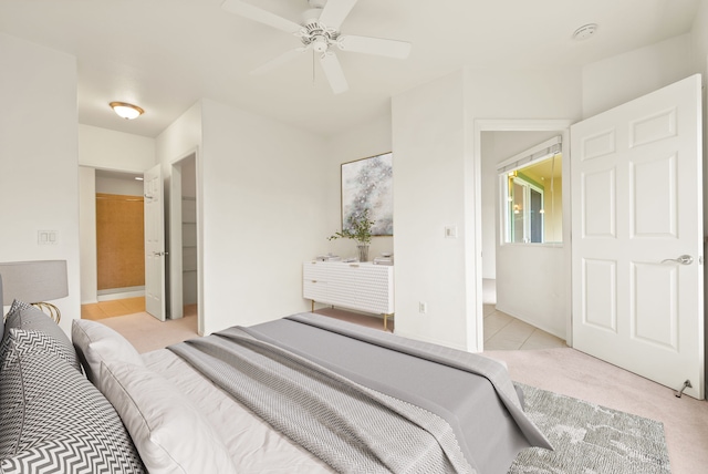 bedroom featuring connected bathroom, ceiling fan, and light colored carpet