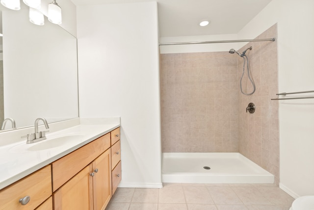 bathroom with tile patterned flooring, vanity, and tiled shower