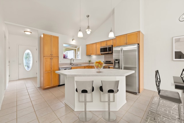 kitchen with stainless steel appliances, light tile patterned floors, a kitchen breakfast bar, high vaulted ceiling, and a kitchen island