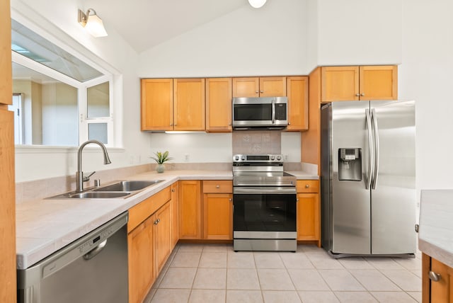 kitchen with sink, light tile patterned floors, stainless steel appliances, and vaulted ceiling