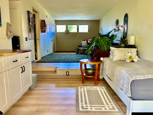 bedroom with a textured ceiling and light wood-type flooring