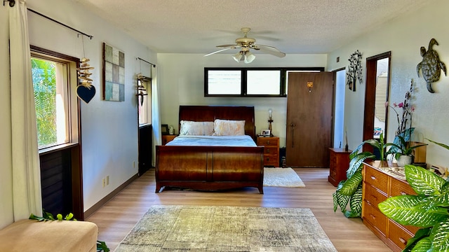 bedroom featuring ceiling fan, light hardwood / wood-style floors, and a textured ceiling