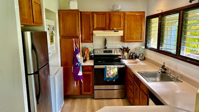 kitchen featuring sink, light hardwood / wood-style flooring, backsplash, washer / clothes dryer, and appliances with stainless steel finishes