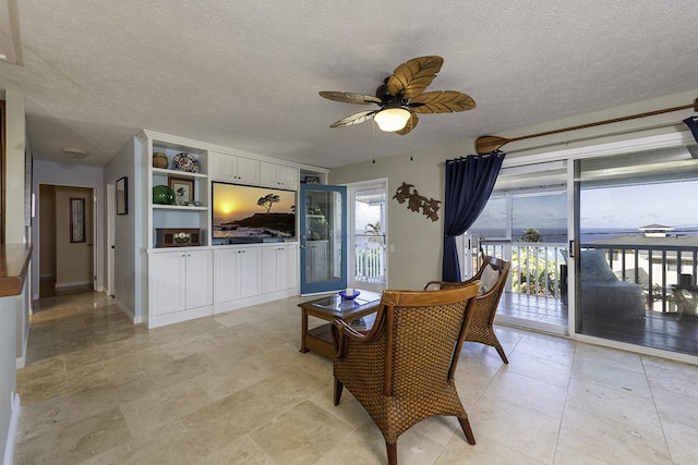 living room featuring ceiling fan and a textured ceiling