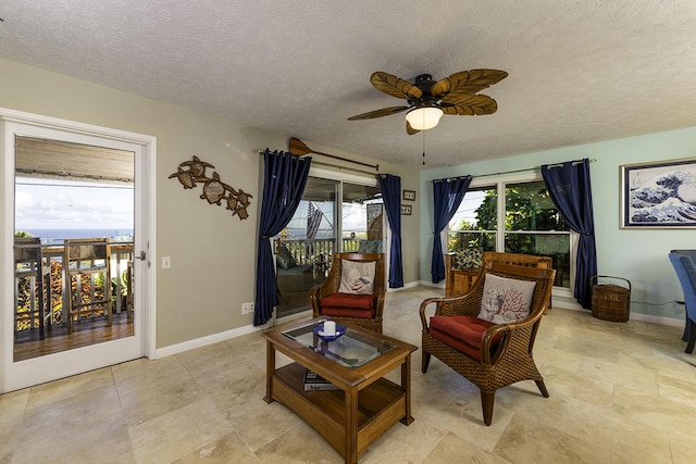 living area with ceiling fan and a textured ceiling