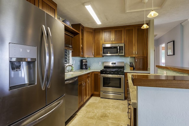 kitchen with sink, decorative backsplash, a textured ceiling, appliances with stainless steel finishes, and decorative light fixtures