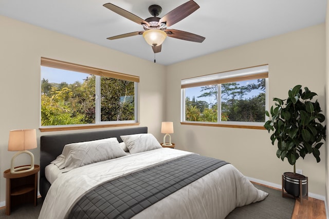 bedroom featuring multiple windows, dark hardwood / wood-style floors, and ceiling fan