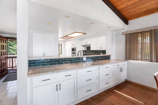 kitchen featuring decorative backsplash, wooden ceiling, vaulted ceiling with beams, light hardwood / wood-style floors, and white cabinetry