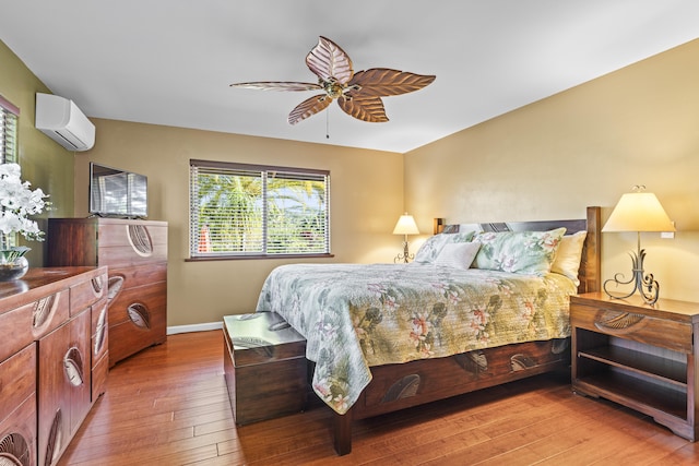 bedroom featuring a wall mounted AC, hardwood / wood-style flooring, and ceiling fan