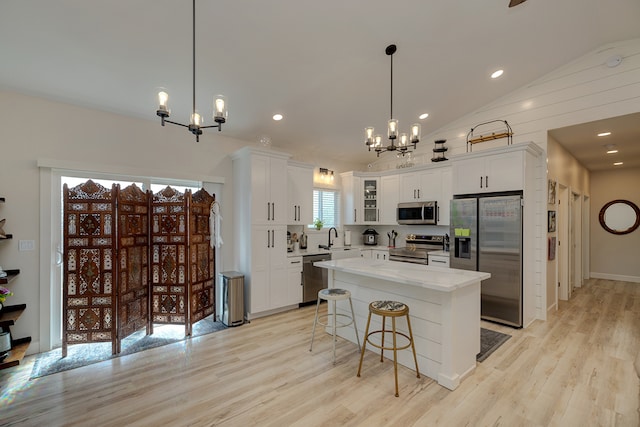 kitchen featuring stainless steel appliances, a chandelier, a center island, light hardwood / wood-style floors, and white cabinetry