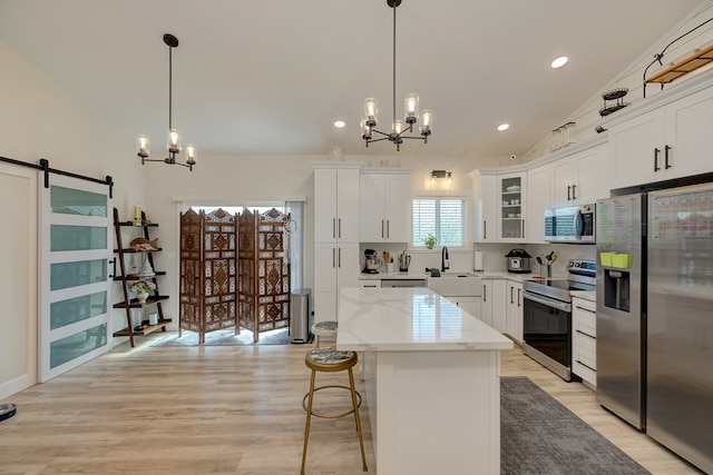 kitchen featuring white cabinetry, a barn door, a chandelier, a kitchen island, and appliances with stainless steel finishes