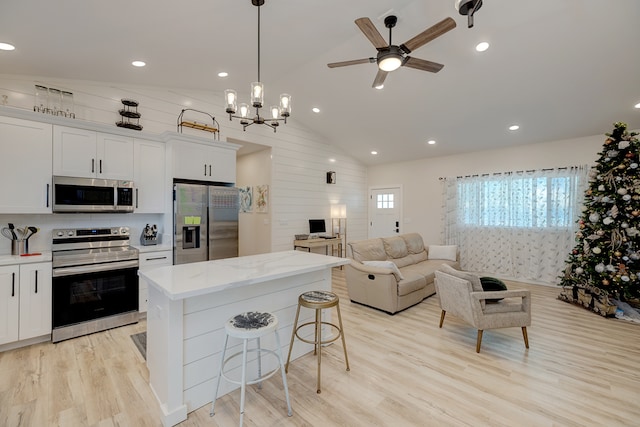 kitchen with a kitchen bar, a center island, stainless steel appliances, and white cabinetry