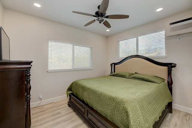 bedroom featuring light hardwood / wood-style flooring, ceiling fan, and an AC wall unit