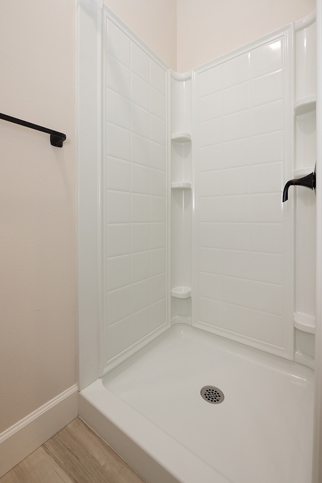 bathroom with hardwood / wood-style flooring and walk in shower