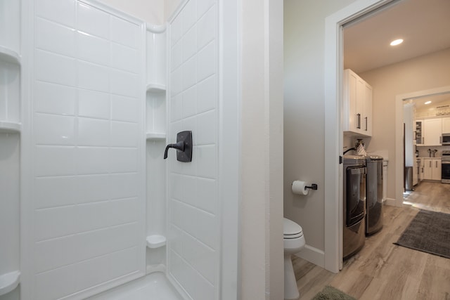 bathroom with hardwood / wood-style flooring, toilet, walk in shower, and washing machine and clothes dryer