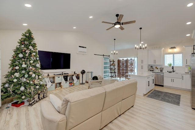 living room featuring light wood-type flooring, ceiling fan with notable chandelier, vaulted ceiling, sink, and a barn door