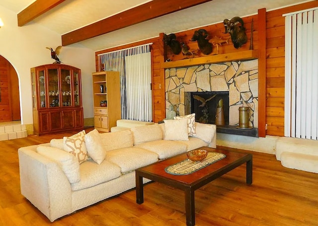 living room with a fireplace, beam ceiling, and hardwood / wood-style flooring