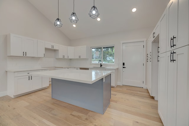 kitchen featuring pendant lighting, a center island, high vaulted ceiling, light hardwood / wood-style flooring, and white cabinetry