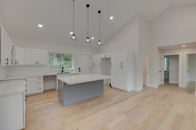 kitchen featuring white cabinets, sink, a kitchen island, and high vaulted ceiling