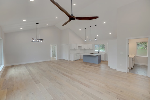 unfurnished living room featuring high vaulted ceiling, light hardwood / wood-style flooring, ceiling fan, and sink