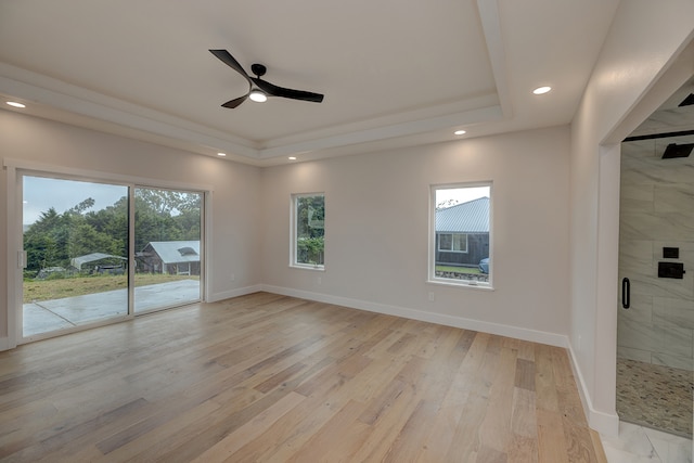 unfurnished room with a tray ceiling, ceiling fan, and light hardwood / wood-style flooring