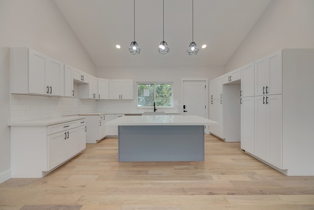 kitchen featuring white cabinets, a center island, and high vaulted ceiling