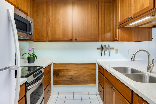 kitchen with light stone countertops, sink, light tile patterned flooring, and stainless steel appliances