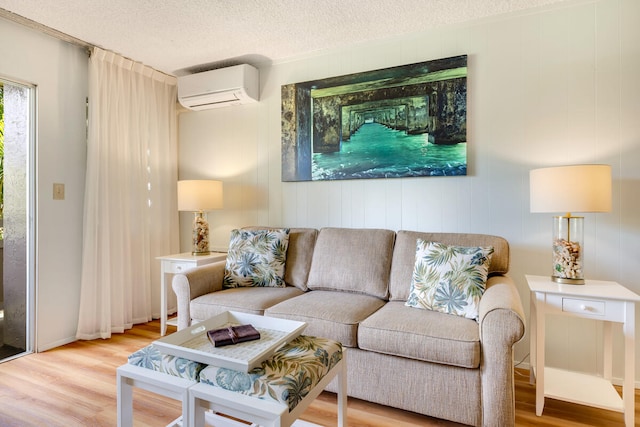 living room with hardwood / wood-style floors, wood walls, an AC wall unit, and a textured ceiling