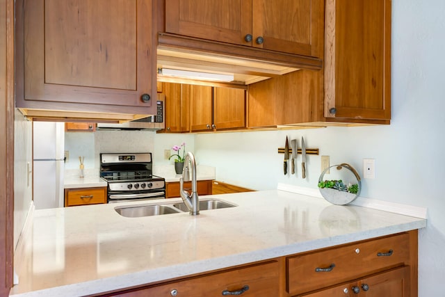 kitchen with light stone counters, sink, and stainless steel range oven