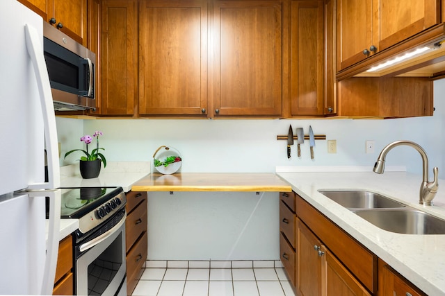 kitchen with light stone counters, light tile patterned floors, sink, and appliances with stainless steel finishes