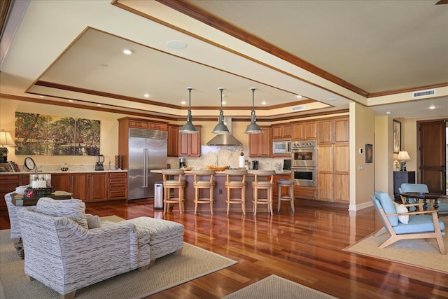 living room featuring dark hardwood / wood-style flooring, ornamental molding, and a tray ceiling