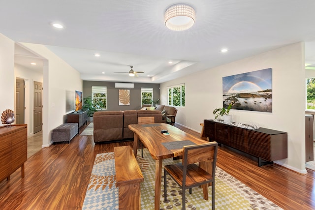 dining area featuring dark hardwood / wood-style floors, a wall unit AC, and ceiling fan