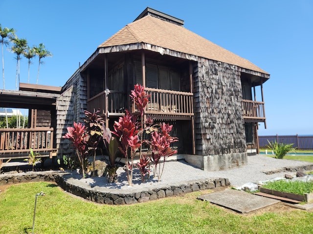 rear view of property featuring roof with shingles and fence