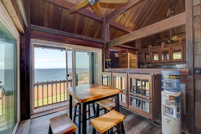 dining space with wooden ceiling, a water view, vaulted ceiling with beams, and wood finished floors