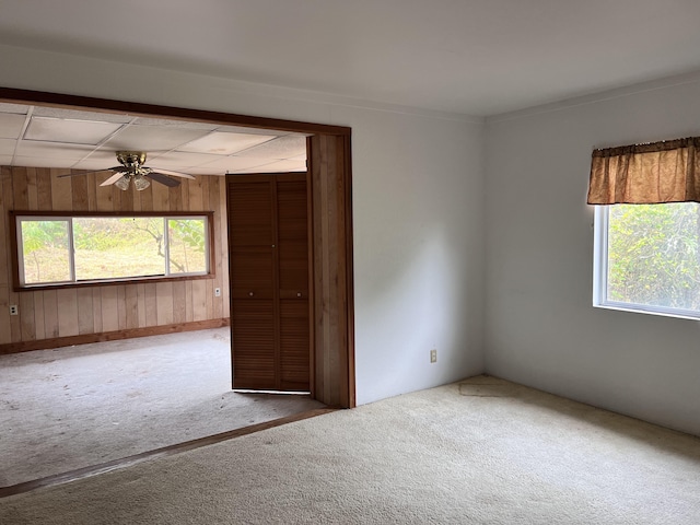 unfurnished room featuring carpet flooring, ceiling fan, and wooden walls