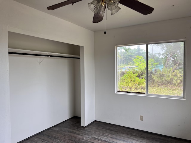 unfurnished bedroom with ceiling fan, dark hardwood / wood-style flooring, multiple windows, and a closet