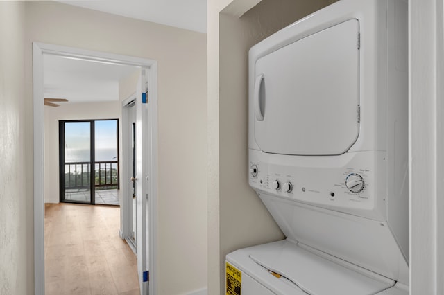 laundry room with ceiling fan, stacked washer and dryer, and light wood-type flooring