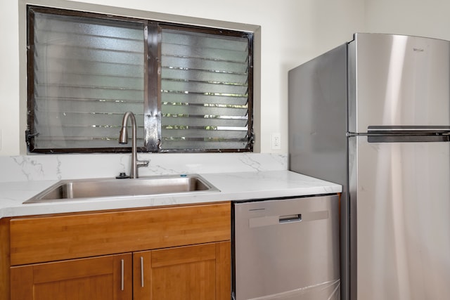 kitchen with light stone countertops, decorative backsplash, sink, and stainless steel appliances