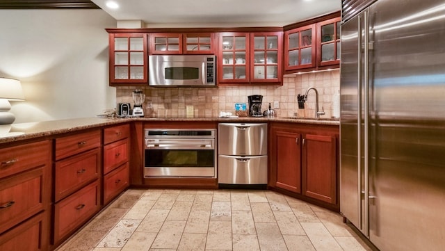 kitchen featuring sink, light stone countertops, stainless steel appliances, and tasteful backsplash