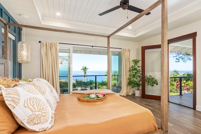 bedroom with hardwood / wood-style floors, ceiling fan, access to exterior, and a tray ceiling