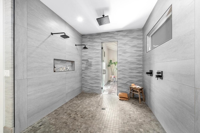 bathroom featuring tile patterned flooring, a tile shower, and tile walls