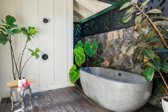 bathroom with beam ceiling, a tub, and hardwood / wood-style floors