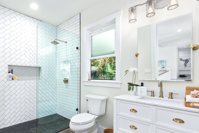 bathroom with tiled shower, vanity, and toilet