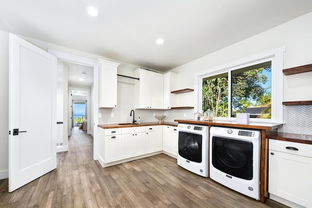 washroom featuring hardwood / wood-style floors, cabinets, sink, and washing machine and clothes dryer