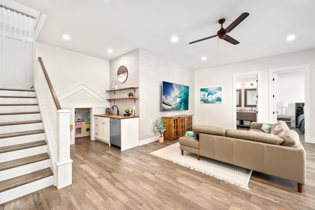 living room featuring light wood-type flooring, ceiling fan, and sink