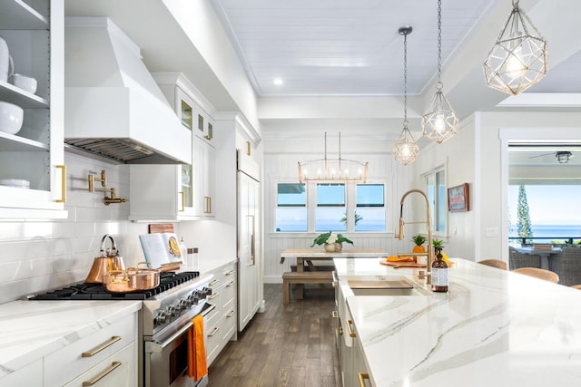 kitchen featuring decorative light fixtures, premium range hood, white cabinetry, and stainless steel stove