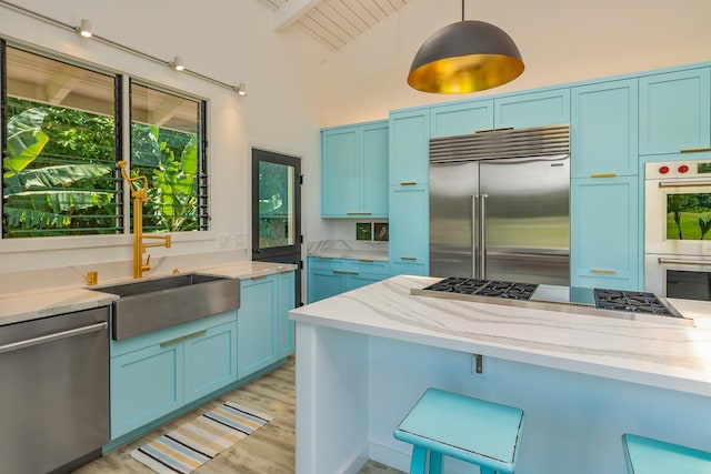 kitchen featuring appliances with stainless steel finishes, sink, blue cabinetry, pendant lighting, and lofted ceiling with beams