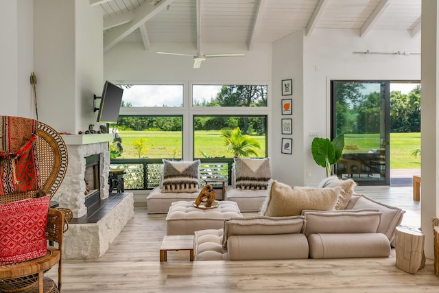 sunroom / solarium featuring ceiling fan, lofted ceiling with beams, and a tile fireplace